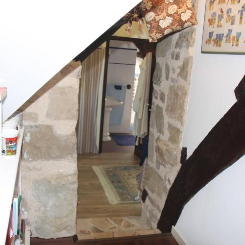 une chambre avec un mur en pierre dans une maison dans l'établissement Le moulin des cavaliers, à La Rouquette