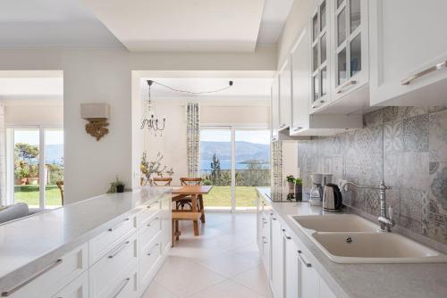 a kitchen with white cabinets and a dining room with a table at Villa Fantasia Isthmia in Isthmia