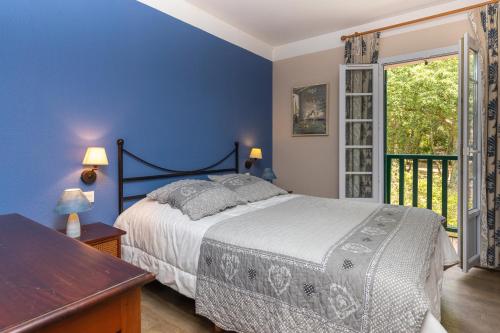 a blue bedroom with a bed and a window at Villa au coeur du golf in Moliets-et-Maa