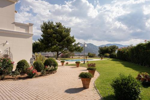a brick walkway with potted plants and a swimming pool at Villa Fantasia Isthmia in Isthmia