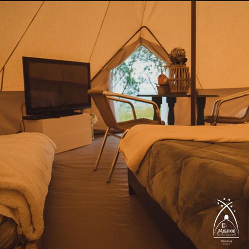 a bedroom with a tent with a tv and a table at Glamping El Mirador de las estrellas in Bojacá