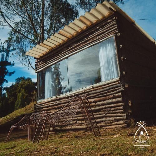 a log cabin with a bench in front of a window at Glamping El Mirador de las estrellas in Bojacá