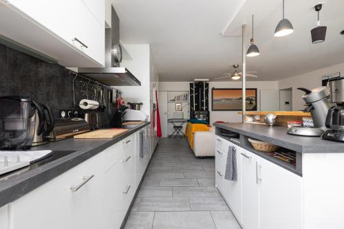 a kitchen with white cabinets and black counter tops at Etchetao in Boucau