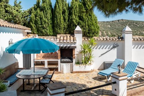 a patio with a table and chairs and an umbrella at Pasa Fina, luxury holiday retreat in Villanueva del Trabuco