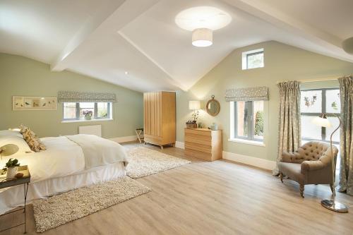 a bedroom with a bed and a chair and windows at The Gardener's Bothy in Shifnal