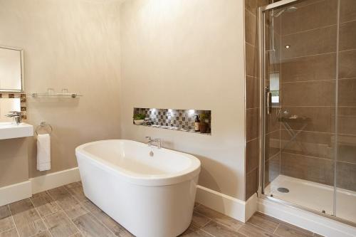 uma casa de banho com uma banheira, um chuveiro e um lavatório. em The Gardener's Bothy em Shifnal
