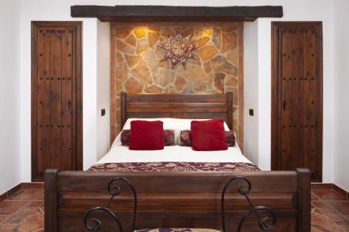 1 dormitorio con cama de madera y almohadas rojas en Pasa Fina, luxury holiday retreat, en Villanueva del Trabuco