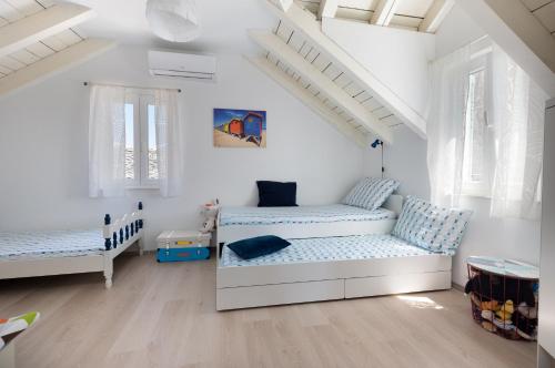 two beds in a room with white walls and windows at Holiday Home Bezic in Grohote