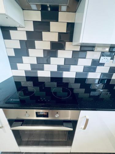 a kitchen with black and white tile on the wall at Deluxe 2 Bedroom Apartment in Sheffield