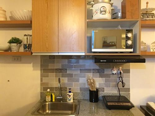 a kitchen counter with a sink and a microwave at La Reina Suite Tuscania Towers in Cagayan de Oro