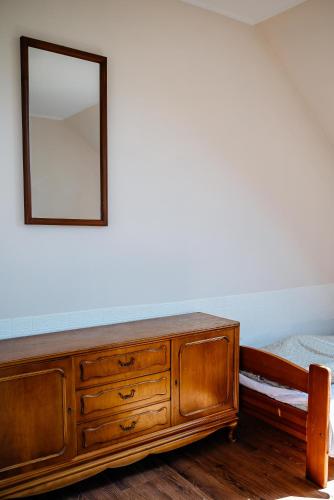 a wooden dresser with a mirror on a wall at Przy Trójstyku in Dubeninki