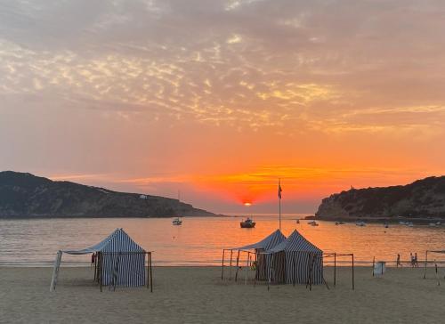 a group of tents on a beach at sunset at Apartamento Bella Vista São Martinho do Porto in São Martinho do Porto