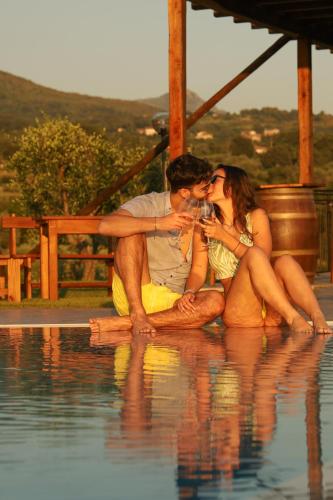 a man and woman sitting next to a swimming pool at L' Aia Resort in Trentinara