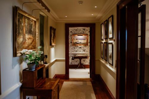 a hallway with a door leading to a room with paintings at Links House at Royal Dornoch in Dornoch