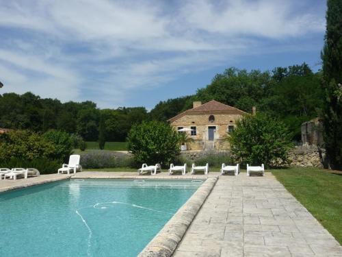 a swimming pool with white chairs and a house at Higat in Eauze