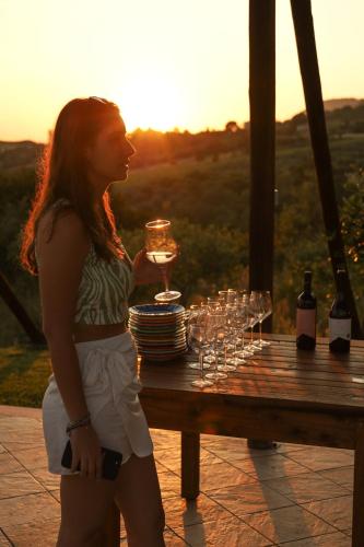 a woman standing next to a table with wine glasses at L' Aia Resort in Trentinara