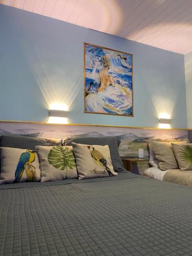 a room with a bed with pillows and a painting on the wall at Fite Suítes in Fernando de Noronha