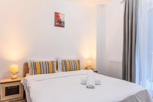 a bedroom with a white bed with two lamps at JAD - Comfortable Family Apartments - Coresi in Braşov