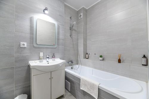 a white bathroom with a sink and a bath tub at JAD - Comfortable Family Apartments - Coresi in Braşov