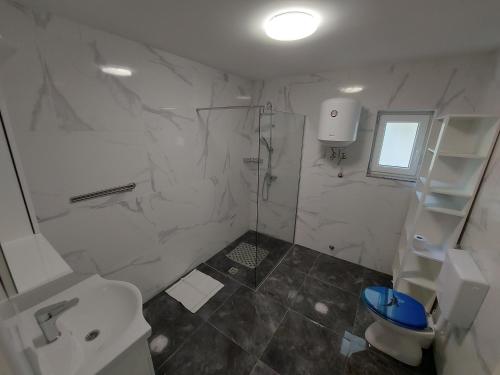 a white bathroom with a toilet and a sink at Apartments Novak in Klenovica