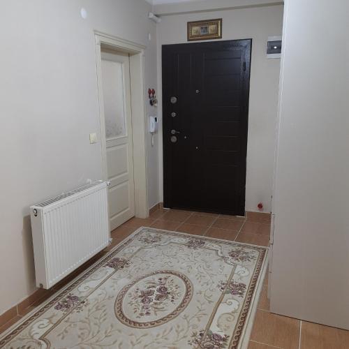 a hallway with a black door and a rug at My Home Araklı in Araklı