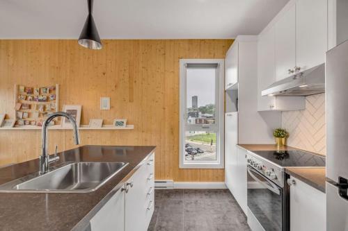 a kitchen with white cabinets and a sink and a window at Initial / Artsy / Centre ville de Quebec in Quebec City