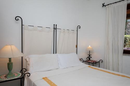 una camera da letto con un grande letto bianco con due lampade di Harry's House by Wonderful Italy a Porto Rotondo