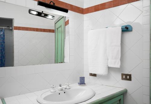 La salle de bains blanche est pourvue d'un lavabo et d'un miroir. dans l'établissement Harry's House by Wonderful Italy, à Porto Rotondo