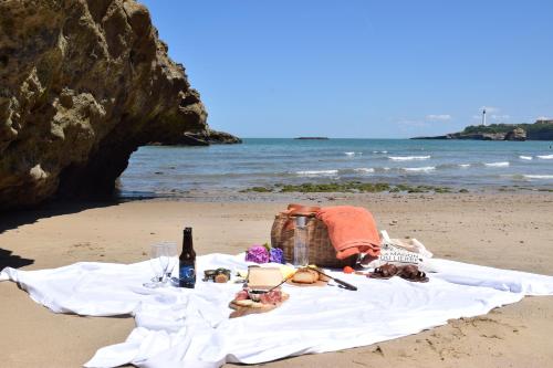 a picnic table on the beach with a bottle of wine at Hôtel & Espace Bien-être La Maison du Lierre in Biarritz