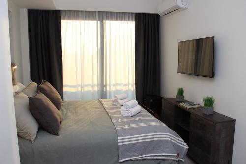 a bedroom with a bed with a television and a window at In House BA - Le coq in Buenos Aires
