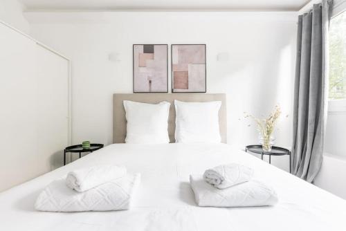 - une chambre blanche avec un grand lit blanc et 2 serviettes dans l'établissement Apartment with balcony next to Buttes Chaumonts, à Paris