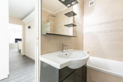 La salle de bains est pourvue d'un lavabo blanc et d'une baignoire. dans l'établissement Apartment with balcony next to Buttes Chaumonts, à Paris