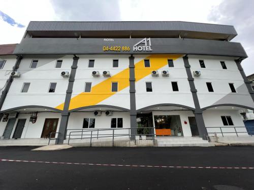 a white building with a yellow and white facade at A1 Hotel Sungai Petani in Sungai Petani