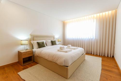 Un dormitorio con una cama grande y una ventana en Viana's Heart - Spacious Modern Ap. Near City Center, en Viana do Castelo