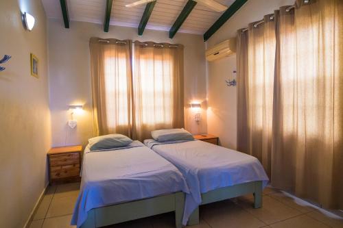 une chambre avec deux lits et une fenêtre avec des rideaux dans l'établissement 28B Casa Kokolishi, à Kralendijk
