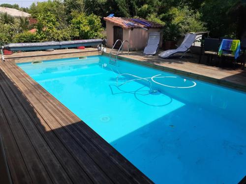 une grande piscine bleue avec une terrasse en bois dans l'établissement Maison avec piscine, à Castelnau-de-Médoc