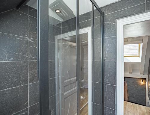 La salle de bains est pourvue d'une douche en verre et de carrelage noir. dans l'établissement Le Rooftop - vue Cathédrale - Climatisation, à Troyes