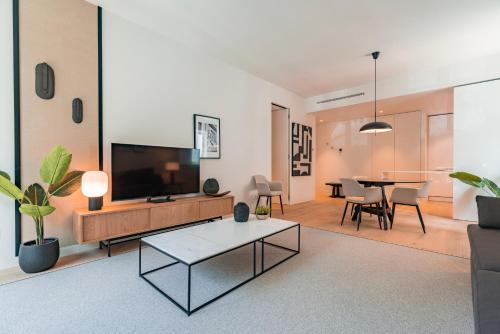 ein Wohnzimmer mit einem TV und einem Tisch in der Unterkunft Liberdade Elegance W/Rooftop Pool by LovelyStay in Lissabon