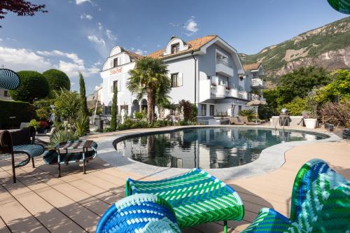 a swimming pool with chairs and a house at Hotel Villa Groff in Ora/Auer