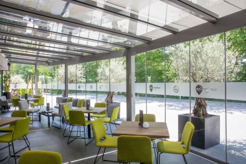 un restaurante con mesas, sillas y ventanas grandes en numberOne Hotel, en Núremberg