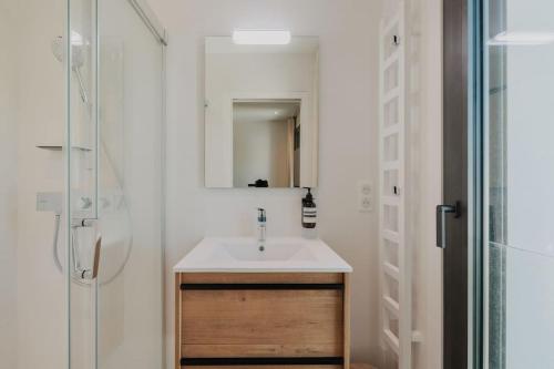 een badkamer met wastafel en douche met spiegel bij Villa Cordouan avec piscine en bord de mer in Royan
