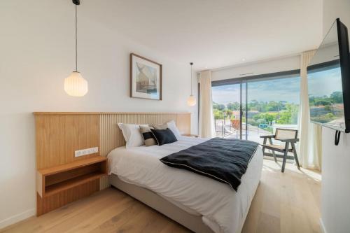 une chambre avec un grand lit et une grande fenêtre dans l'établissement Villa Cordouan avec piscine en bord de mer, à Royan