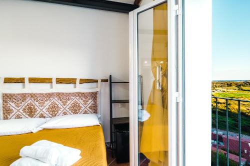 um quarto com uma cama amarela e uma varanda em CAMERA VISTA MARE CASA RAIMONDA Ammentos Posada em Posada