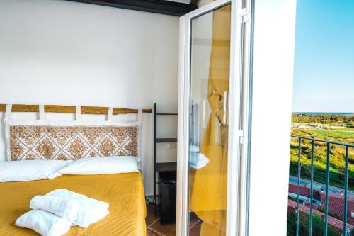 um quarto com uma cama amarela e uma varanda em CAMERA VISTA MARE CASA RAIMONDA Ammentos Posada em Posada