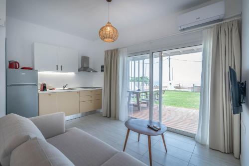 a living room with a couch and a table and a kitchen at Thea Eco Suites in Nea Kallikrateia