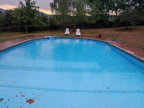 una gran piscina azul con 2 sillas en un patio en casa rural usko en Amurrio