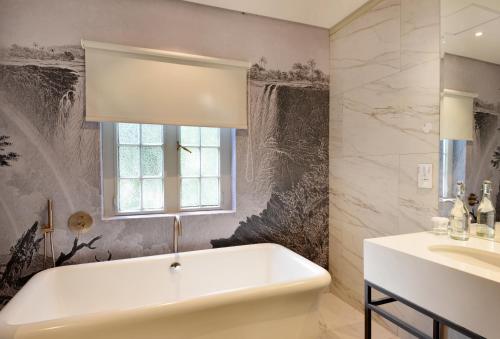 a bathroom with a tub and a sink and a window at The Victoria Falls Hotel in Victoria Falls