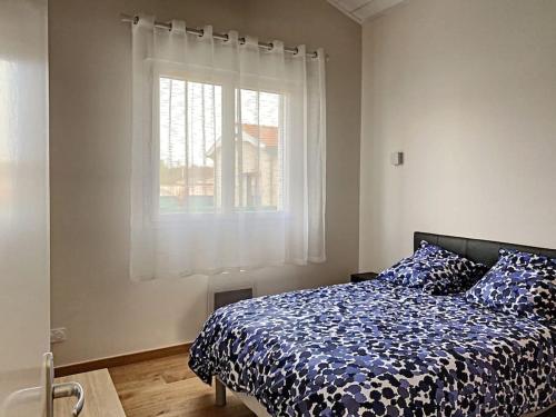 une chambre avec un lit avec une couette bleue et une fenêtre dans l'établissement Maison la teste, à La Teste-de-Buch