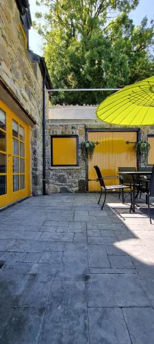 a patio with two benches and an umbrella at Frontview Cottage - Two Bedroom - Sleeps 6 guests in Ballynahinch