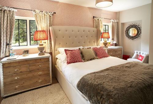 a bedroom with a large bed and a dresser and windows at Pink Cottage in Shifnal